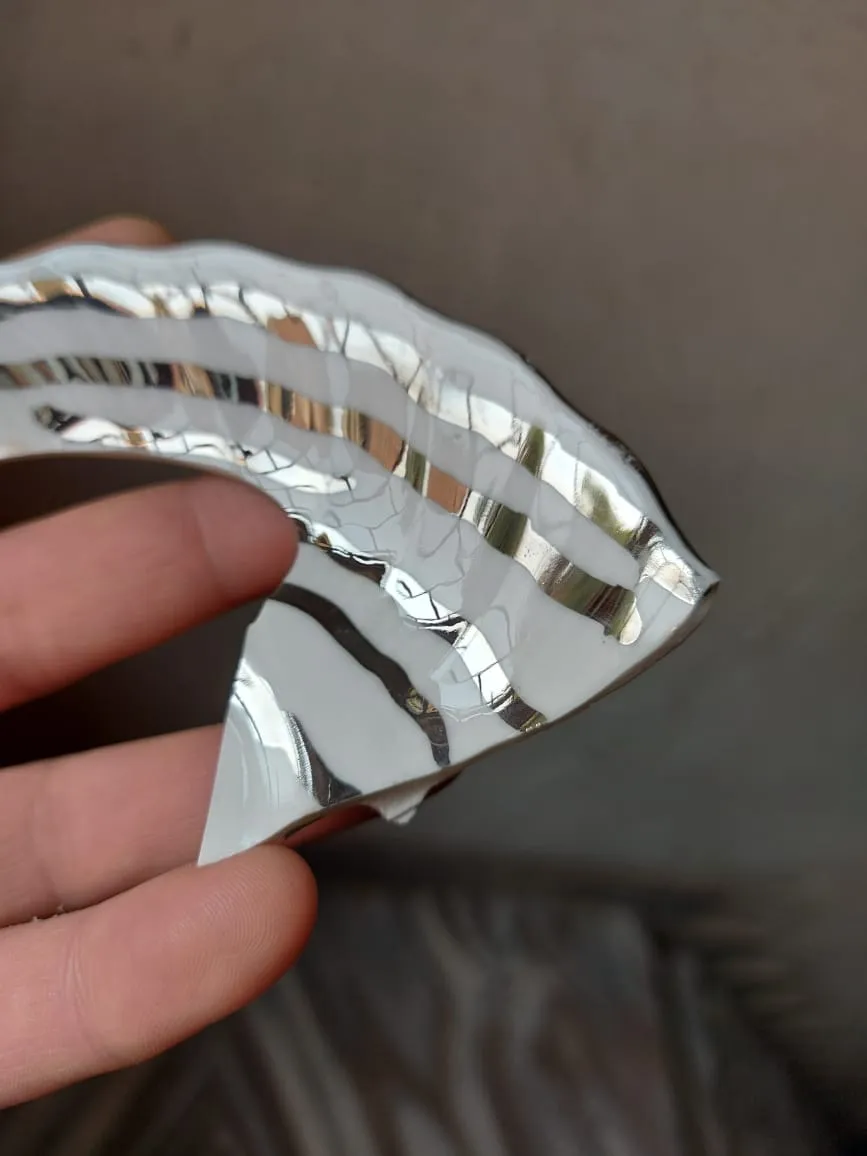 A glass piece with bands of liquid platinum, held in a hand